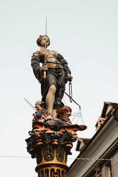 女人拿着剑和资产规模雕像在白色的天空

